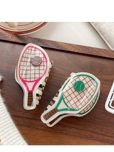 Detail view of pink and green tennis racket hair claws on a dark wooden tray
