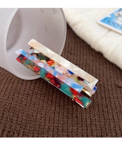 Close-up of three rectangle acetate hair clips with marble and floral patterns
