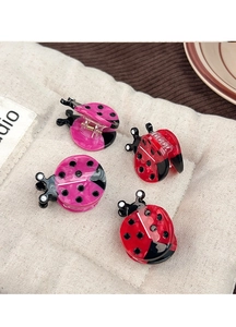Detailed view of four ladybug hair clips in red and pink colors on soft fabric background