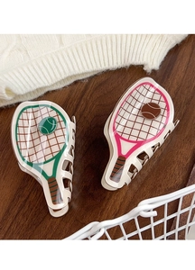Detail of tennis racket hair clips in green and pink on a rustic wooden surface