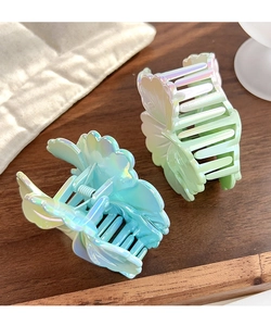 Gros plan de pinces à cheveux fleur dégradé irisé en bleu et vert sur du bois