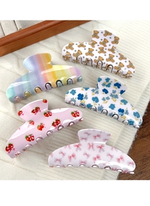Lot de cinq pinces à cheveux motifs ours, fraise et nœud sur un tissu en maille blanche
