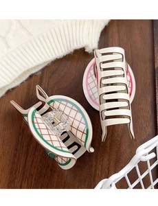 Detail of tennis racket hair claw clip and beige hair grab on dark wood background