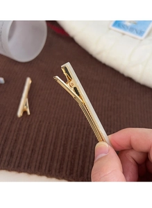 Detail of a minimalist gold metal duckbill hair clip with creamy white acrylic inlay