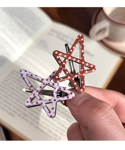 Close-up of star-shaped hair clips with polka dots in brown and white resin finish