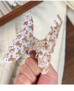 Détail d'une pince à cheveux papillon avec oursons mignons et motifs floraux