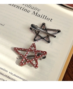 Star-shaped hair clips with red polka dots and silver metal frame on vintage books
