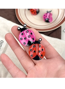 Close-up of shiny ladybug hair clips in red and pink acetate finish with black dots