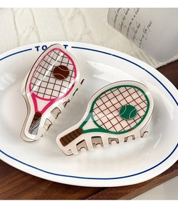 Close-up of creative tennis racket hair claws in pink and green on a white plate