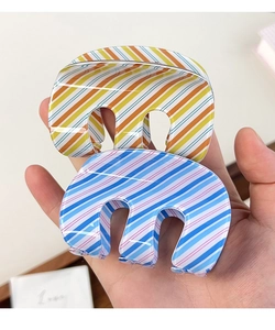 Detailed view of large striped claw clips for hair styling in orange and blue patterns