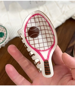 Detail of a white PVC tennis racket shark clip showing the mesh pattern and brown ball decor