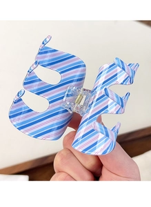Detail of the striped claw clip showing blue and pink patterns with transparent spring