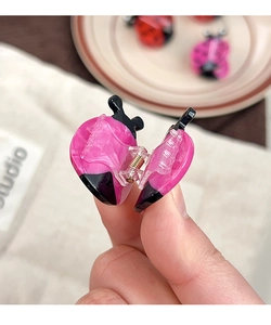 Close-up of pink and black ladybug hair claw clip made of acetic acid and metal spring