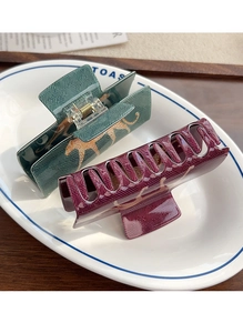 Close-up of leopard pattern hair claws in dark green and burgundy on ceramic tray