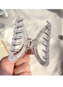 Gros plan d'une pince à cheveux papillon transparente avec ressort doré et dents lisses