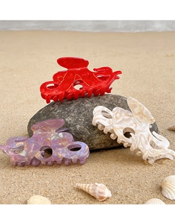 Détail de pinces à cheveux poulpe en acétate coloré sur le sable avec coquillages