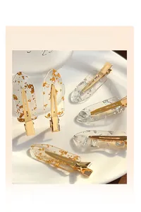 Detail of transparent resin hair clips with embedded gold and silver foil in a ceramic dish