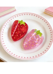 Detailed close-up of pink and red strawberry hair claws in a decorative ceramic dish