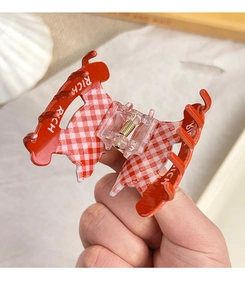 Détail d'une pince à cheveux à carreaux rouges et blancs avec ressort doré et RICH