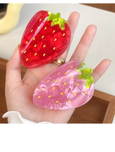 Detailed view of large strawberry hair claws with red and pink marble acetate texture