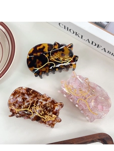 Dettaglio delle mollette per capelli a gatto in acetato con motivi tartaruga, rosa e marrone