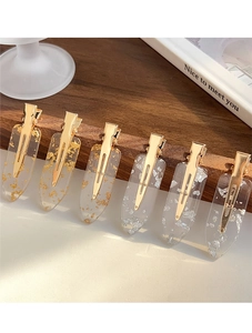 Detail of six transparent resin hair clips with gold and silver foil on a wooden stand