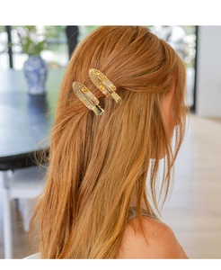 Detailed view of two transparent resin hair clips with gold foil on a female model