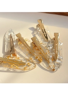 Detailed macro view of clear resin hair clips with embedded gold and silver foil flakes