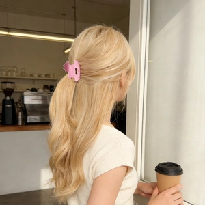 Pince à cheveux mate rose avec texte Rich Rich portée par un mannequin blond au café
