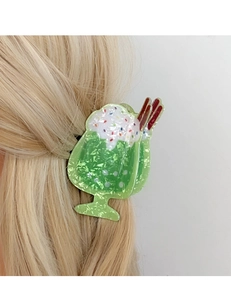 Dettaglio di un fermaglio per capelli a forma di dessert verde su capelli biondi mossi