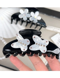 Detailed close-up of a premium acetate hair claw with white butterfly and floral rhinestone accents