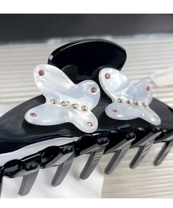 Close-up of black claw clip featuring pearlescent white butterflies and pink rhinestones