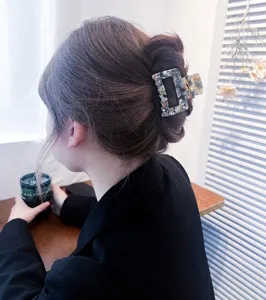 Detailansicht einer eleganten quadratischen Haarklammer aus Acetat auf braunem Haar.