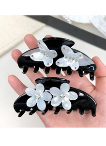 Close-up of black acetate hair claws featuring rhinestone flowers and pearlescent butterflies