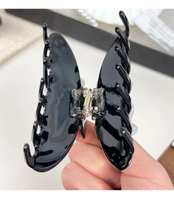Detailed view of black butterfly hair claw with golden metal spring and smooth finish