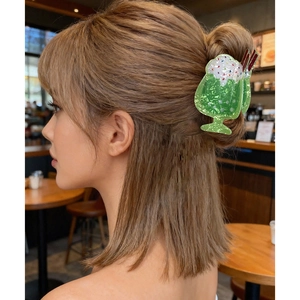 Pinza per capelli creativa a forma di tazza di soda verde indossata su una modella