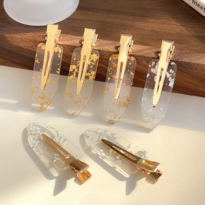 Set of 6 transparent hair clips with gold and silver foil inlays on a wooden display