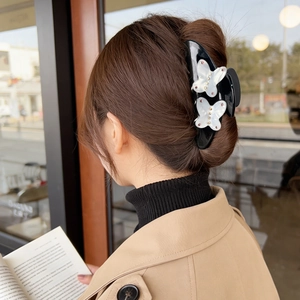 Black butterfly hair claw clip with white acetate floral accents for thick hair styling