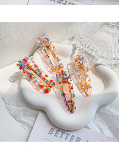 Detail of colorful polka dot acetate hair clips with gold metal base on a white tray
