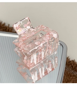 Detail of square acrylic hair claw clip with pink crushed stone texture and mirror reflection