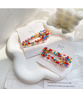 Detail of acrylic hair clips with colorful confetti pattern on a white display card