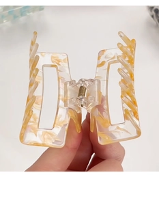 Detail of a rectangle cream marble acetate hair claw clip with geometric hollow design