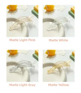Detailed view of matte textured wave-shaped hair clips in pink, white, grey, and yellow