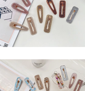 Macro shot of acetate hair clips with marble patterns and glitter finishes on a tray