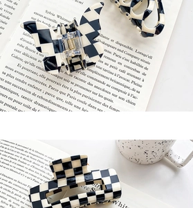 Detail of checkered acetate hair claw clips with black and white pattern on french book background