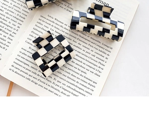 Detailed view of checkered acetate hair claws placed on an open vintage book page