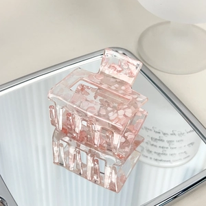 Pink translucent acrylic hair claw clip with crushed stone texture on mirror tray