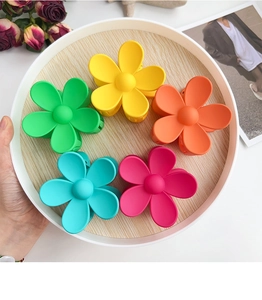 Set of five matte candy-colored floral hair claws arranged in a decorative tray