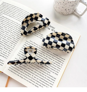 Three-piece set of checkerboard acetate hair claws on a vintage book backdrop