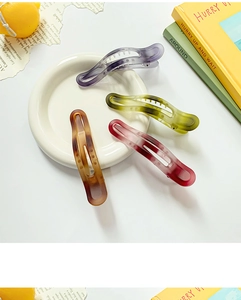 Close-up of matte gradient hair clips in Morandi colors on white ceramic tray